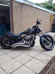 a black and chrome motorcycle parked in front of a brick building next to a sidewalk