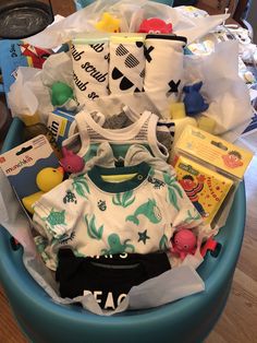 a blue basket filled with baby items on top of a wooden floor