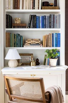 a bookshelf filled with lots of books next to a white desk and chair