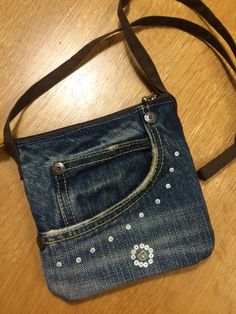 a denim purse with flowers on it sitting on a wooden floor