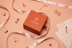 an orange box sitting on top of a pink surface next to some other jewelry items