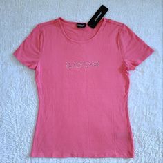 Brand New With Tags Bebe Coral Ribbed Top With Clear Rhinestones Excellent Condition With No Flaws Size Large Approx Measurements Laying Flat: Length 23" Armpit To Armpit 17" Across Bottom Hem 17.5" 94% Rayon 6% Spandex Color Of Top Is Coral (I Feel It Is More Of A Salmon Color With More Pinkish Than Orange Tones) With "Bebe" On Upper Front In Clear Rhinestones Ribbed Material, Rounded Neckline, Short Sleeves, Straight Hem, Significant Stretch Please No Trades Or Lowballs! *Ask Any Questions You Cabin 10, Bebe Shirts, Batwing Shirt, Cold Shoulder Styles, Purple Tee, Rhinestone Top, Orange Tones, Sweet Shirt, White Tee Shirts