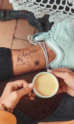 a person with a tattoo on their arm holding a coffee cup