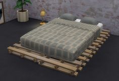 a bed sitting on top of a wooden pallet next to a potted plant