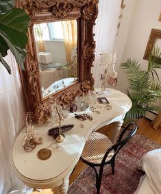 a white desk with a mirror on top of it next to a chair and potted plant