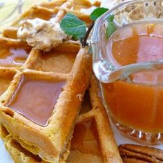 waffles with syrup and butter are on a plate next to a glass of orange juice