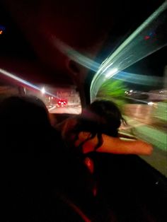 a woman sitting in the passenger seat of a car at night with her hand on her head