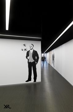 a man standing in front of a painting on the wall next to a long hallway