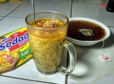 a cup of soup and a bag of noodles on a table with a spoon in it