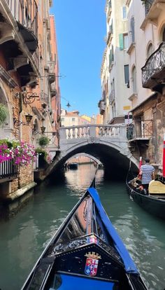 a boat traveling down a river next to tall buildings and flowers on the side of it