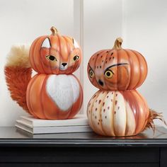 two pumpkins with faces painted on them are sitting on a shelf next to each other