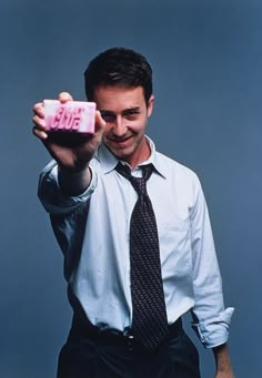 a man holding up a pink camera to take a selfie with his thumb in the air