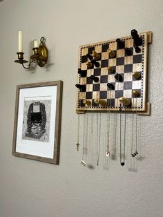 a chess board hanging on the wall next to a framed photograph and some keys attached to it