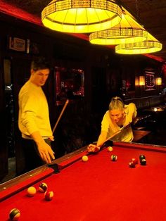 two men are playing pool in a bar