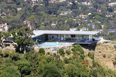 an aerial view of a house on top of a hill with a pool in the foreground