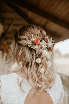 a woman with flowers in her hair wearing a white dress and holding a flower crown