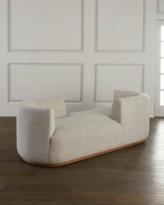 a white couch sitting on top of a wooden floor next to a wall with paneled panels