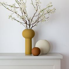 two vases with flowers in them sit on a shelf next to an egg holder