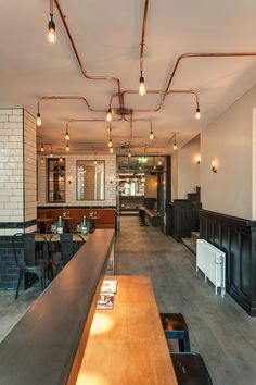 an empty restaurant with wooden tables and black bar stools in front of the counter