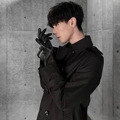 a man with black hair wearing a trench coat and gloves