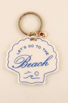 a white and blue keychain with the words, let's go to the beach on it