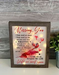 a wooden frame with the words missing you on it next to a potted plant