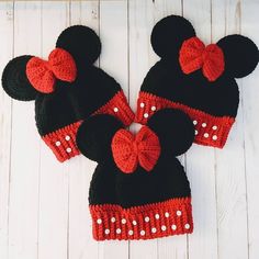 two crocheted minnie mouse hats with red bows on white wood background, top view