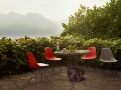 a man sitting at an outdoor table with four chairs around him and the view of mountains in the distance