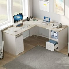 a computer desk with two computers on top of it in a living room next to a window