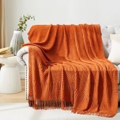 an orange blanket is draped over a white couch