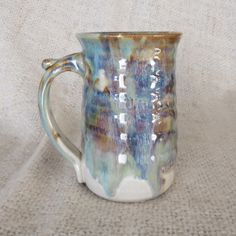 a blue and white coffee mug sitting on top of a cloth covered tablecloth,