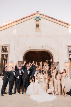 a large group of people standing in front of a white building with their arms up