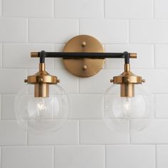 two clear globe lights mounted on a white tiled wall