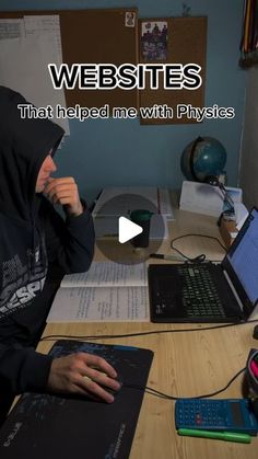 a man in a hoodie sitting at a desk with two laptops on it