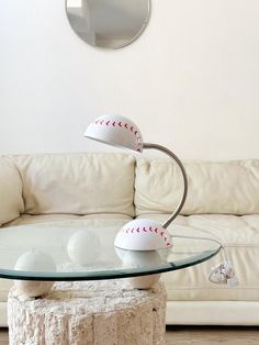 a glass table with baseballs on it in front of a white couch and mirror