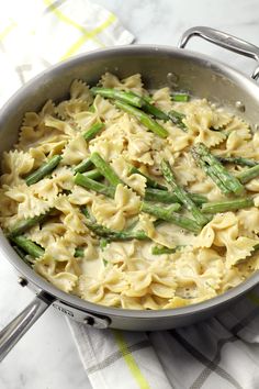 a pan filled with pasta and asparagus on top of a white table cloth