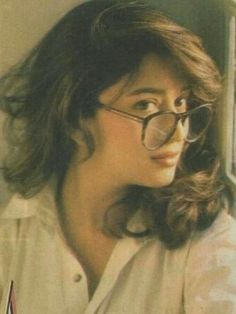 a woman wearing glasses looking out the window with her hair blowing in the wind,