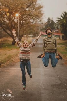 two people jumping in the air on a road