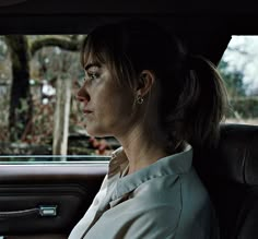 a woman sitting in the back seat of a car with her head turned to the side