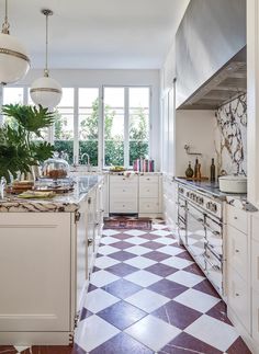 a kitchen with checkered tile flooring and white cabinetry, along with potted plants