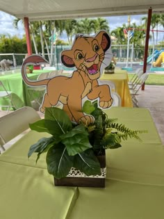 the lion cub centerpiece is sitting on top of a green table cloth with a potted plant