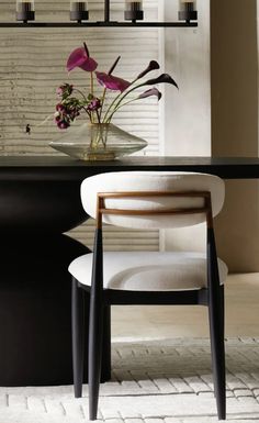 a vase with flowers sitting on top of a table next to a chair and candle holder