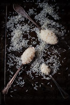 three spoons with rice on them are sitting on a table next to silverware