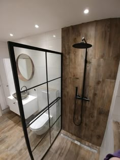 a bathroom with a toilet, shower and wooden flooring in the middle of it