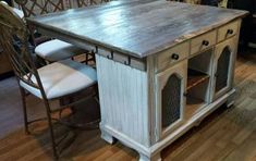 a kitchen island with two chairs and a table in front of it on top of a hard wood floor