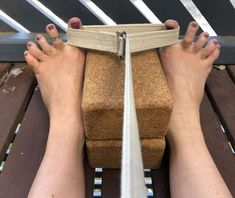 a woman's feet on a wooden bench with straps around her ankles and toenails