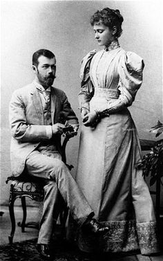 an old black and white photo of a man sitting on a chair next to a woman