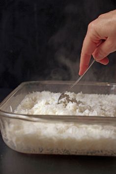 a person is spooning rice into a casserole dish