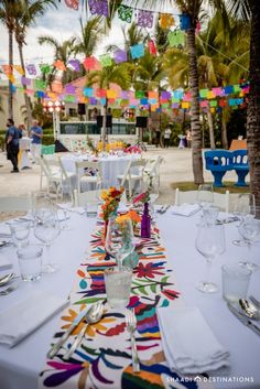 the table is set up for an event with white linens and colorful paper decorations