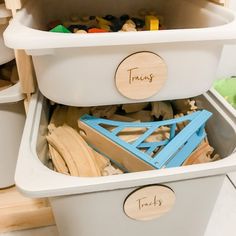 a toy storage bin filled with wooden toys and personalized name tags on the lid